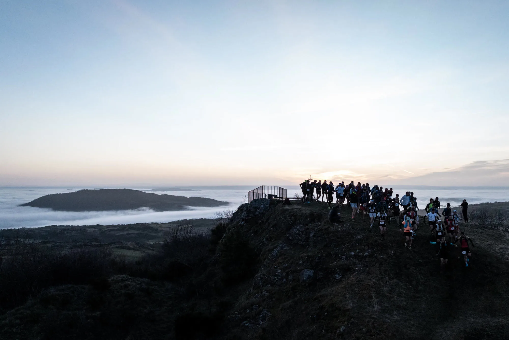 Peloton de La Romagnatoise sur la crête au lever du jour, au-dessus d'une mer de nuages